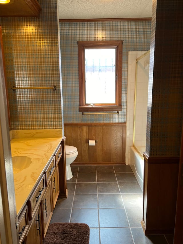 full bathroom featuring shower / bath combination, vanity, a textured ceiling, tile patterned floors, and toilet