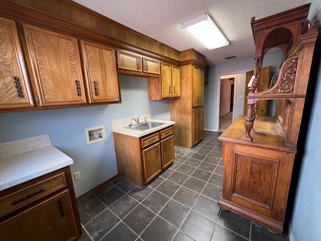 kitchen featuring sink, dark tile patterned flooring, and a textured ceiling