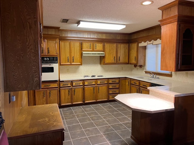 kitchen with sink, white appliances, a textured ceiling, dark tile patterned flooring, and kitchen peninsula