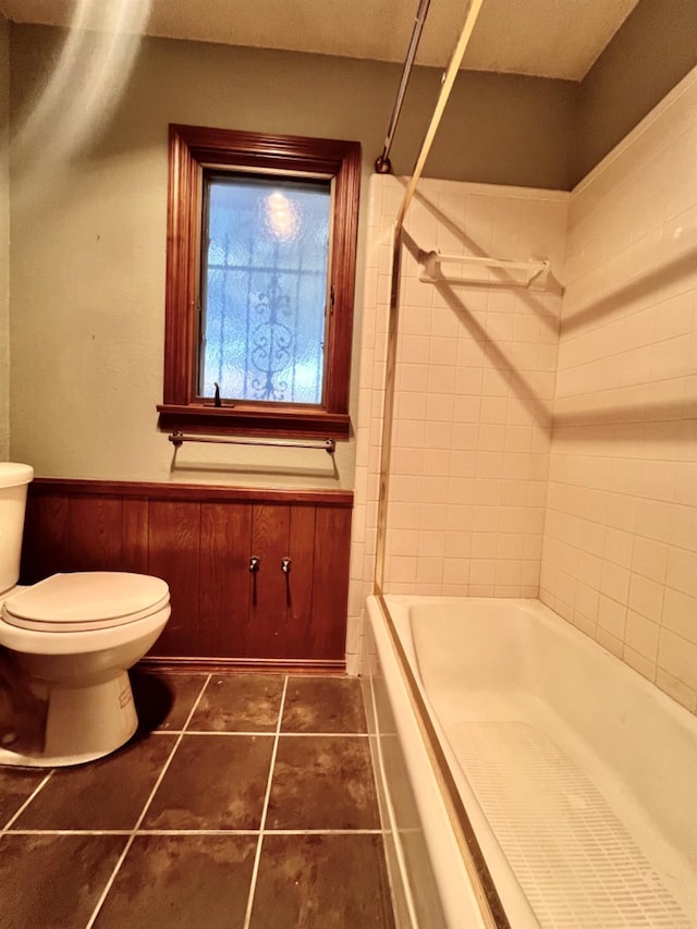 bathroom featuring tile patterned flooring, tiled shower / bath, and toilet