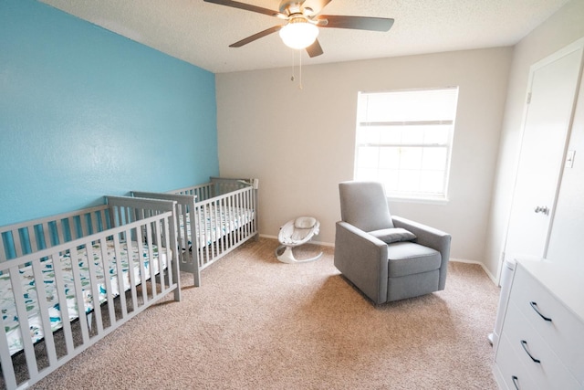 bedroom with ceiling fan, light carpet, and a textured ceiling