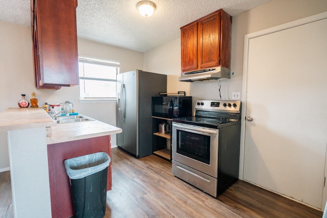 kitchen featuring appliances with stainless steel finishes, sink, light hardwood / wood-style floors, and a textured ceiling