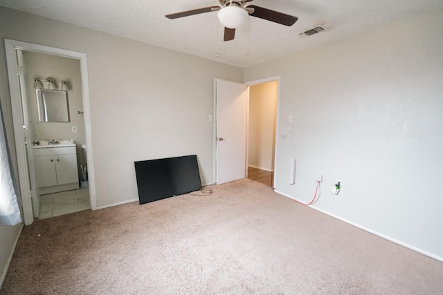 unfurnished bedroom featuring ceiling fan, carpet floors, sink, and ensuite bath