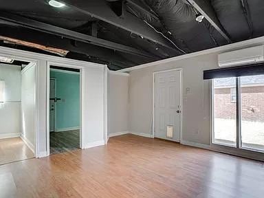 basement featuring hardwood / wood-style flooring and an AC wall unit