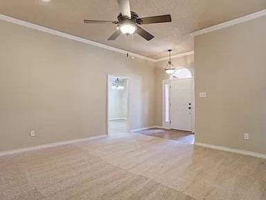 carpeted entryway with crown molding and ceiling fan