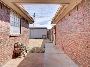 view of property exterior featuring a storage unit and a patio area