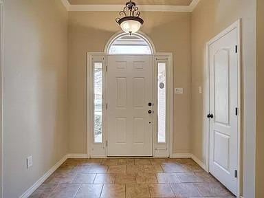 foyer with ornamental molding and a healthy amount of sunlight