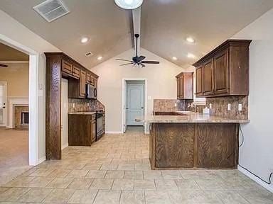 kitchen featuring backsplash, ceiling fan, kitchen peninsula, and vaulted ceiling with beams