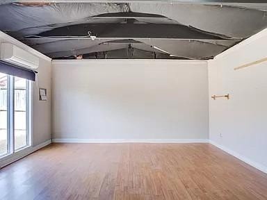 empty room featuring plenty of natural light, light hardwood / wood-style flooring, and an AC wall unit