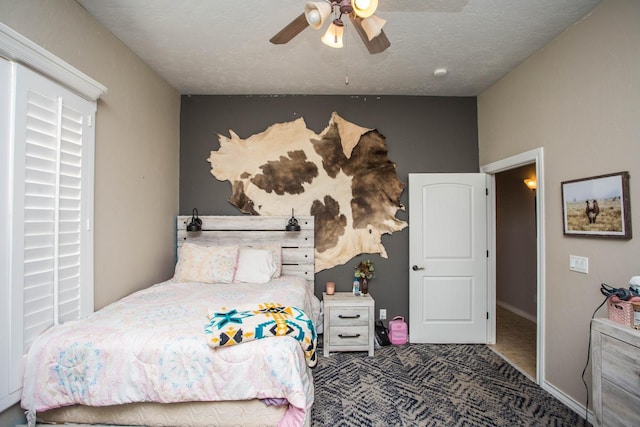 carpeted bedroom featuring ceiling fan and a textured ceiling