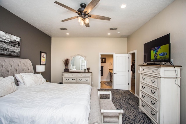 bedroom featuring ceiling fan, connected bathroom, and dark carpet