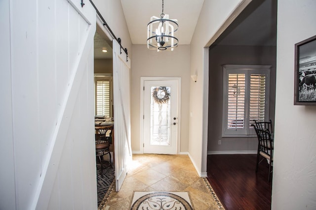 foyer entrance featuring hardwood / wood-style flooring, a barn door, and a chandelier