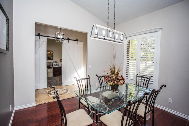 dining area with lofted ceiling, hardwood / wood-style floors, and a barn door