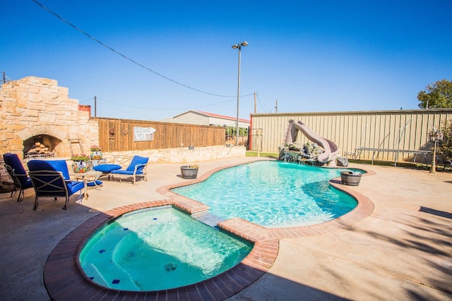 view of pool with an in ground hot tub, a patio, and a water slide