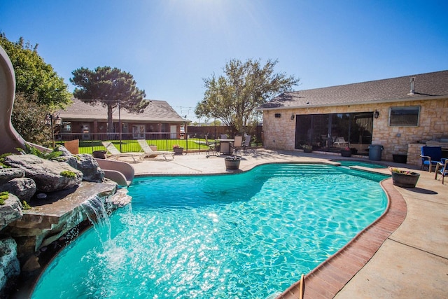 view of pool with a patio, pool water feature, and a water slide