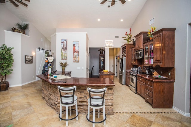 kitchen featuring pendant lighting, a breakfast bar, ceiling fan, stainless steel appliances, and a barn door