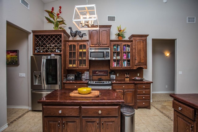 kitchen featuring tasteful backsplash, light tile patterned floors, stainless steel appliances, and a center island