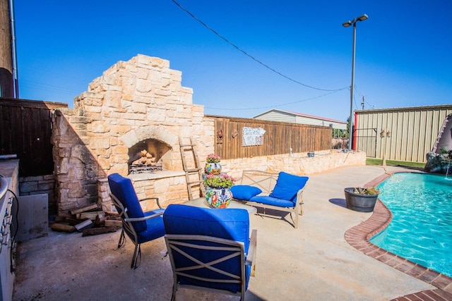 view of patio featuring pool water feature, a fenced in pool, and an outdoor stone fireplace