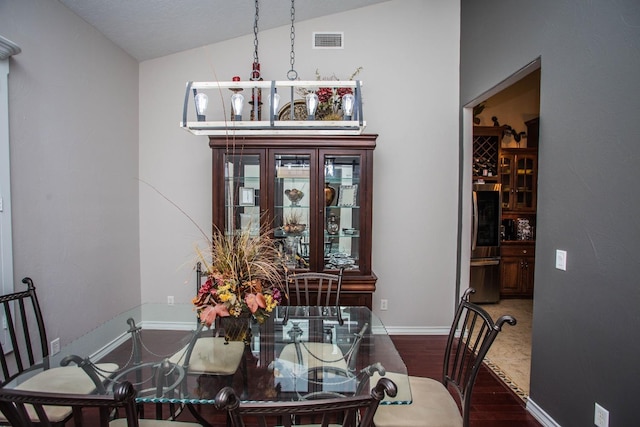 dining space featuring hardwood / wood-style flooring and vaulted ceiling