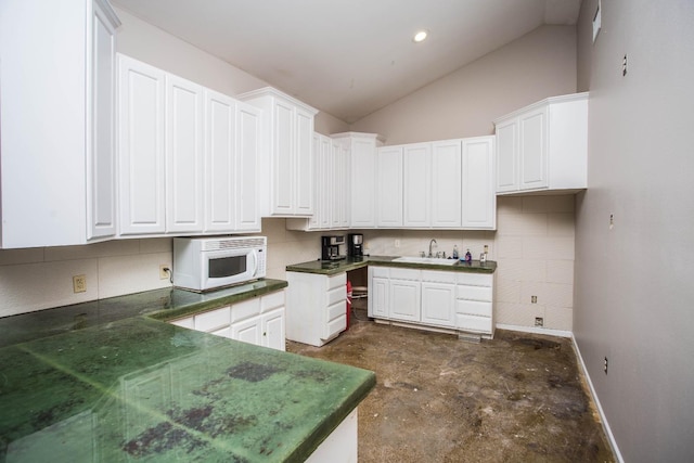 kitchen featuring white cabinetry, lofted ceiling, sink, and decorative backsplash