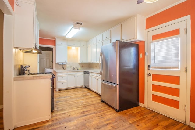 kitchen featuring appliances with stainless steel finishes, backsplash, white cabinets, and light hardwood / wood-style floors