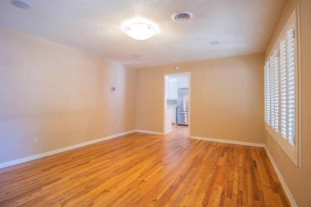 unfurnished room featuring a textured ceiling and light wood-type flooring