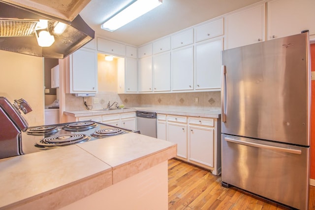 kitchen with sink, light hardwood / wood-style flooring, appliances with stainless steel finishes, decorative backsplash, and white cabinets