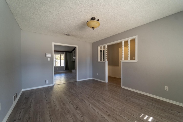 spare room featuring dark wood-type flooring and a textured ceiling