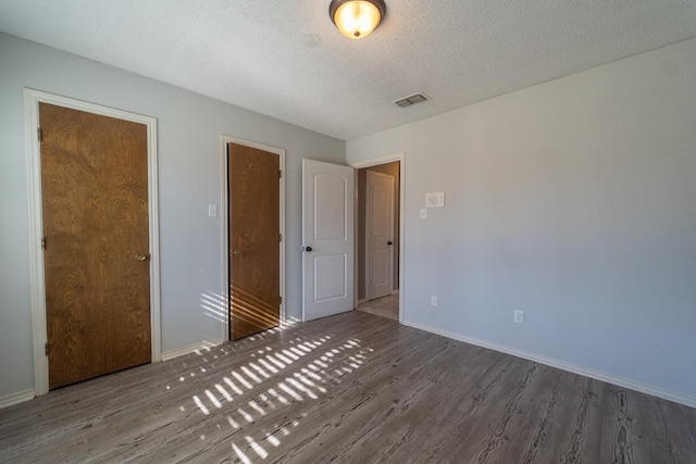 unfurnished bedroom with hardwood / wood-style flooring and a textured ceiling