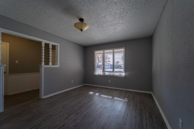 spare room featuring dark wood-type flooring and a textured ceiling