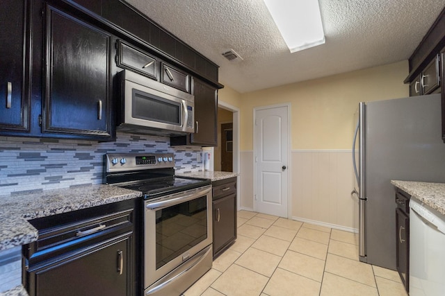 kitchen featuring light tile patterned floors, light stone countertops, a textured ceiling, and appliances with stainless steel finishes