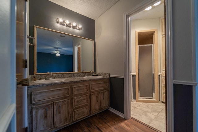 bathroom with a shower with door, vanity, wood-type flooring, and a textured ceiling