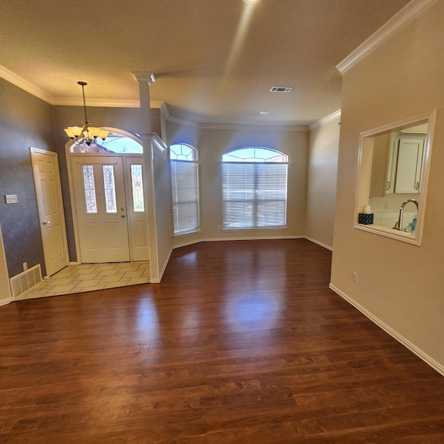 foyer with a chandelier, visible vents, and wood finished floors