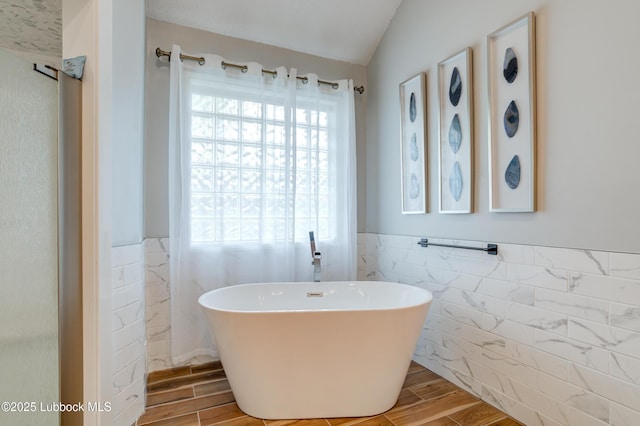 4801 Amherst St, Lubbock, TX 79416 - bathroom with tile walls, plenty of natural light, wood finish floors, a soaking tub, and a wainscoted wall