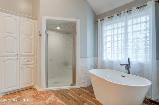 4801 Amherst St, Lubbock, TX 79416 - full bathroom featuring tile walls, a shower stall, a freestanding bath, wood finished floors, and wainscoting