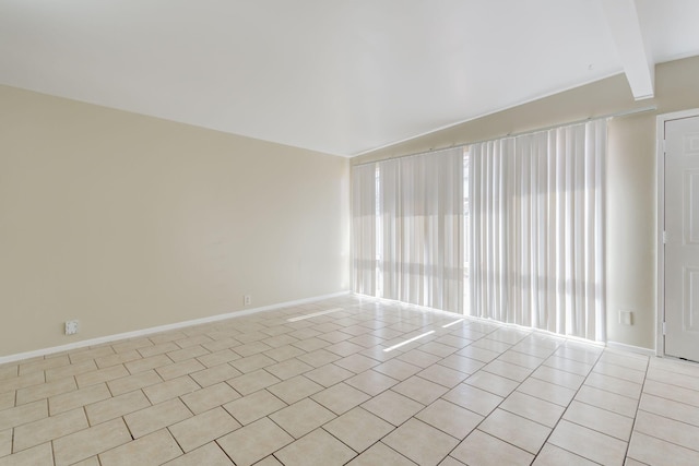 tiled empty room featuring beam ceiling