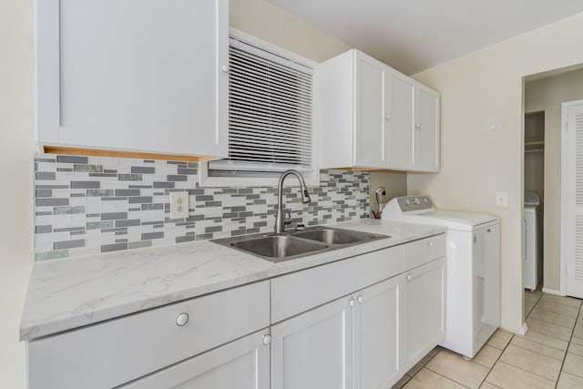 kitchen featuring washer / clothes dryer, sink, and white cabinets