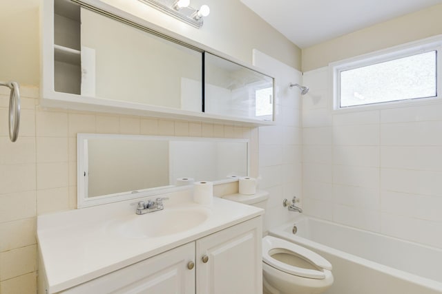 full bathroom with vanity, toilet, tiled shower / bath combo, and tile walls