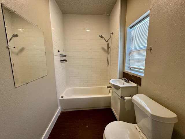 full bathroom with vanity, tiled shower / bath combo, toilet, and a textured ceiling