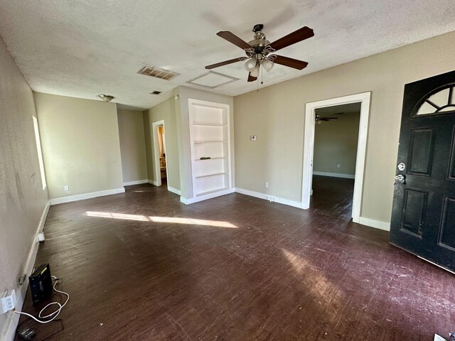 unfurnished living room featuring ceiling fan, dark hardwood / wood-style floors, built in features, and a textured ceiling