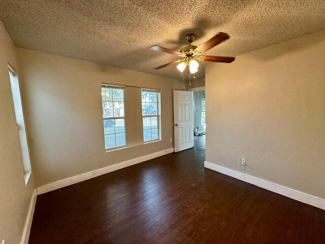 unfurnished room with a textured ceiling, dark wood-type flooring, and ceiling fan