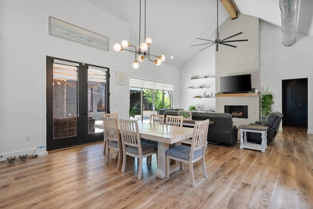 dining area featuring high vaulted ceiling, a fireplace, light wood-style floors, french doors, and beamed ceiling