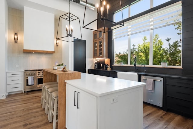 kitchen featuring dark wood-type flooring, white cabinetry, decorative light fixtures, appliances with stainless steel finishes, and a kitchen island