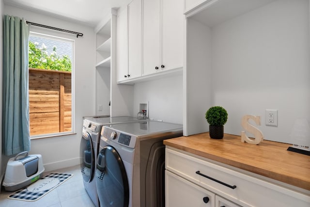 laundry room featuring light tile patterned floors, washing machine and dryer, and cabinets