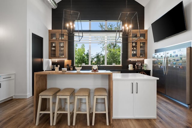 kitchen featuring built in fridge, hardwood / wood-style flooring, a chandelier, and kitchen peninsula