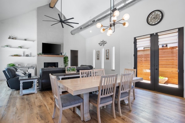 dining space with french doors, high vaulted ceiling, light wood-style flooring, and a fireplace