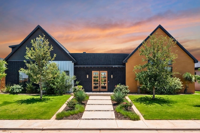 view of front of property with french doors and a lawn