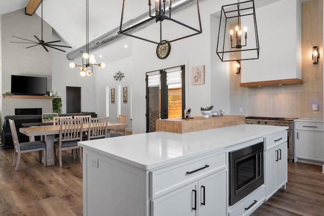 kitchen with stainless steel microwave, white cabinets, dark hardwood / wood-style flooring, hanging light fixtures, and a center island