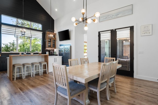 dining room featuring an inviting chandelier, high vaulted ceiling, and hardwood / wood-style floors