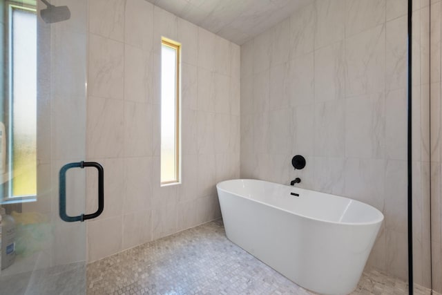 bathroom with tile walls, a stall shower, and a freestanding bath